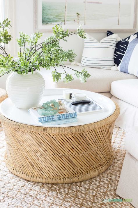 A coastal bamboo coffee table with white enamel tray top that is durable and great for indoor or outdoor use! Decorated with a vase of greenery, a blue and white linen tray for TV remotes, and various beach inspired books and glass beads. Coastal Coffee Table Decor, Neutral Couch, Coastal Coffee Table, Life On Virginia Street, Bamboo Coffee Table, Den Ideas, Rattan Coffee Table, Summer Home, Blue Throw Pillows