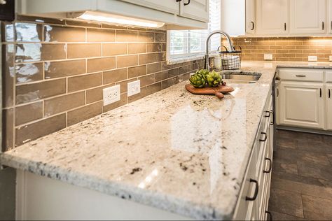 Light brown subway tiles with white grout in a modern kitchen. Colonial White countertops with under counter lighting and white cabinets. Dark brown-grey mixed contemporary porcelain tiles flooring. Beautiful light green wall paint and dark hardware. A subway tile backsplash always gives a timeless vibe to the kitchen. #colonialwhitegranite #colonialwhitegranitecountertops #lightbrownbacksplash #whitekitchencabinets #browngraymixedporcelainfloortiles #colonialwhitegranitekitchencountertops White Granite Kitchen Countertops, Colonial White Granite, Kitchen Countertop Colors, Light Colored Granite, White Granite Countertops Kitchen, Light Granite Countertops, White Granite Colors, Brown Granite Countertops, Granite Kitchen Countertops