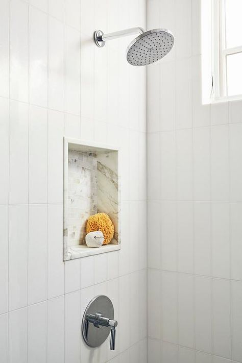 Walk-in shower is clad in white vertical wall tiles and fitted with a chrome round rain shower head fixed over a mosaic marble tiled niche. Tiled Niche, Chrome Shower Fixtures, Shower Accent Tile, Tile Walk In Shower, White Tile Shower, Tile Backsplash Bathroom, Subway Tile Showers, Mosaic Marble, Subway Tiles Bathroom