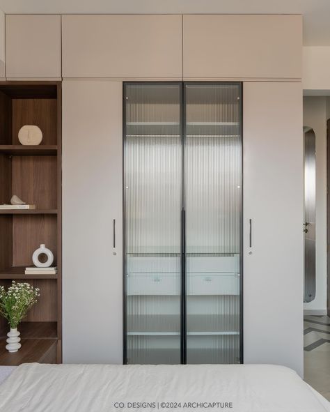 | Emerald retreat | Guest bedroom | Effortlessly blending functionality with style, this guest bedroom’s floor pattern draws you into a space where open and closed storage is accented by elegant glass shutters. The custom-shaped full-height mirror cleverly positioned behind the door amplifies the room, while the bespoke stone light adds a dash of whimsy. #codesigns #SmartDesign #GuestRoomChic #MirrorIllusion #bedroomdesign Photograohy by : @archi.capture_ [ Bedroom Design, Flute glass... Glass Shutter Wardrobe, Mirror Illusion, Glass Wardrobe, Floor Pattern, Wardrobe Designs, Chic Spaces, Mirror Design, Bedroom Mirror, Flute Glass