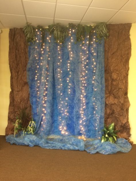 My own waterfall. I'm so thrilled because I had all the materials on hand to make this one. 3 blue plastic tablecloths, wrinkled brown paper, "water" gossamer fabric, and two tired looking floral greenery pieces that I deconstructed for my "plants". Water Theme Decorations, Kids Room For Two, Paper Waterfall, Trendy Classroom, Waterfall Decoration, Classroom Door Ideas, Wrinkled Paper, Vbs Themes, Water Wall