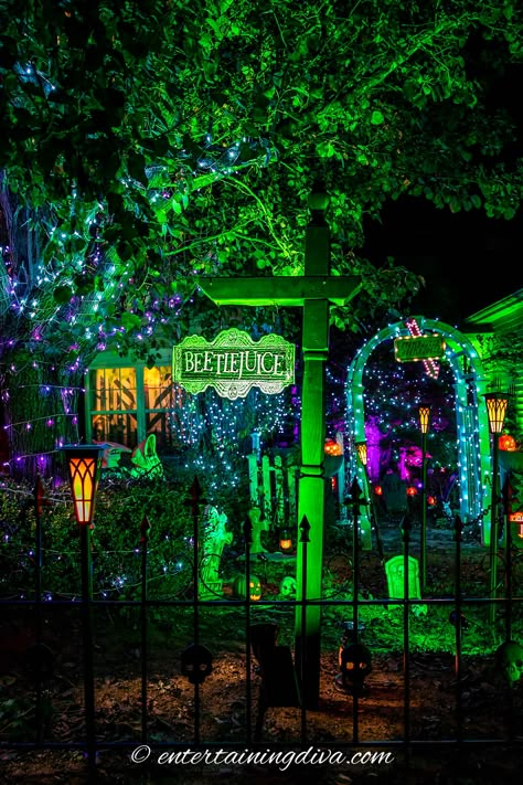 Beetlejuice-themed house lit up with green and purple lights. Beetlejuice House Decor Outside, Universal Monsters Halloween Decor, Halloween Movie Yard Decorations, Beetlejuice Front Yard, Tim Burton Halloween Decor Outdoor, Beetlejuice Haunted House, Halloween Beetlejuice Decorations, Beetlejuice House Decor, Beatle Juice Halloween Decor