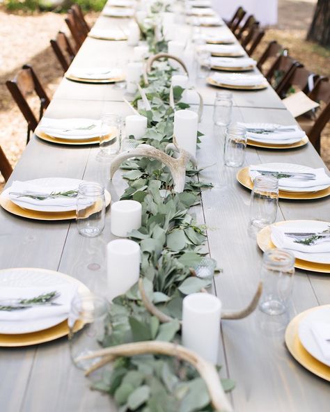 I loved how our Henderson Farm Tables looked lined up as a head table for this Lake Tahoe wedding  the gorgeous eucalyptus runner from Foothill Flowers looked perfect with the Antlers & Pillar Candles  and the Gold Chargers were perfect with the simple place settings  simple rustic mountain wedding  perfection!  @melaniesoliel  #tinrooffarmhouse #weddingrentals #lakewedding #mountainwedding #laketahoewedding #outdoorwedding #farmtable #farmhousedecor #headtabledecor #weddingdesign #weddingstylis Camo Wedding Decorations, Rustic Wedding Table Setting, Wedding Candles Table, Rustic Mountain Wedding, Flowers Eucalyptus, Wedding Themes Spring, Antler Wedding, Camo Wedding, Wedding Table Flowers