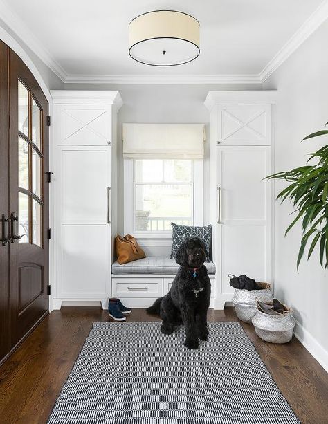 Mudroom designed with a built-in bench centered between tall shaker cabinets with nickel pulls flanking a window with an ivory roman shade. Transitional Laundry Room, Mudroom Cabinets, Mudroom Lockers, Led Ceiling Light Fixtures, Mudroom Design, Modern Crystal Chandelier, Shaker Cabinets, Built In Bench, Mudroom Bench