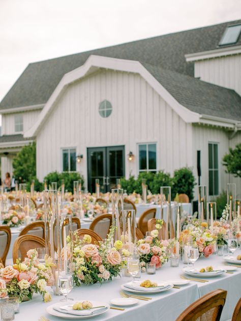 Pink peach rose, pink coral garden rose, blush spray rose, yellow lisianthus, white delphinium, feverfew chamomile, peach ranunculus - glass candlesticks, white and champagne sand taper candles - farm table centerpiece Floral Runner Wedding, Yellow Lisianthus, Wedding Farm Table, Farm Table Centerpiece, Candle Tablescapes, White Delphinium, Lime Wedding, Yellow Centerpieces, Baby Pink Wedding