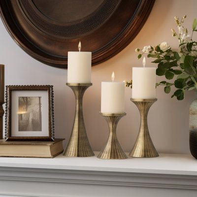 Add a luxe look to your space with this set of 3 handcrafted aluminum candle holders. Finished in a rich antique pewter or brass patina for a mid-century modern-inspired look, this stunning set features handcrafted etched details to highlight your home décor with a dramatic presence. These pillar candle holders make a gorgeous display when placed in the living room or entryway, especially on a shelf or mantle. Try these alone or as a grouping in the bedroom or bathroom to add an elegant touch or Brass Candle Holders Decor, Aluminum Candle, Pillar Candle Holder, Brass Patina, Dream Cabin, Town Home, Brass Candle Holders, Pillar Candle Holders, Brass Candle