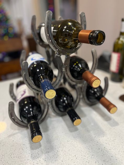 Recycled horseshoes made into a distinctive wine rack. Holds 6 bottles of wine. Horse Shoe Shoe Rack, Horse Shoe Boot Rack, Horse Shoe Wine Rack, Horse Shoe Wine Bottle Holder, Horseshoe Wine Rack, Horse Shoe Crafts Without Welding, Wine Bottle Rack, Metal Working Projects, Shoe Crafts