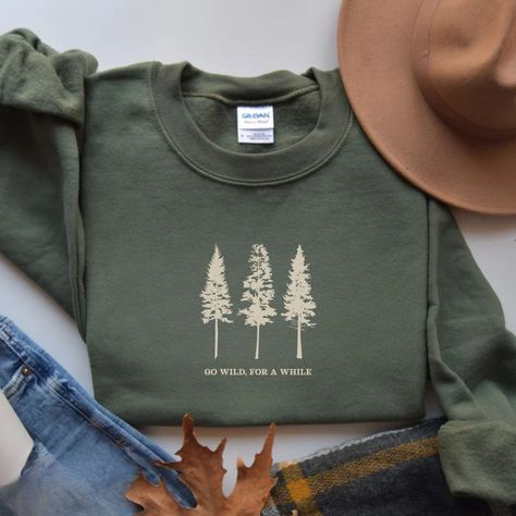 Embrace the spirit of adventure with our Pine Tree Sweatshirt featuring the phrase "Go Wild, For a While" and a stunning graphic. Perfect for nature lovers, this hiking and camping crewneck makes an ideal gift for granola girls and travel enthusiasts who crave the great outdoors and the freedom of the wilderness. Prefer this design on a T-Shirt? Visit this link: https://bohemianbloomdesigns.etsy.com/listing/1772284433 Prefer this design on a Hoodie? Visit this link: https://bohemianbloomdesigns. Outdoorsy Shirt, Baggy T-shirt, Hiking And Camping, Mountain Shirt, Mama Style, Granola Girl, Branded Sweatshirts, Dressy Outfits, Classic Outfits