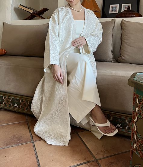 The ivory white brocade kimono. This exquisite garment is a timeless classic, exuding grace and refinement. Shop our Eid collection now and elevate your wardrobe with this stunning piece. Festive White Long Abaya, Elegant Abayas White, White Open Abaya, Elegant White Embroidered Abaya, Moroccan Clothes, White Bohemian Floor-length Abaya, Arabic Fashion, Moroccan Clothing, Church Fits