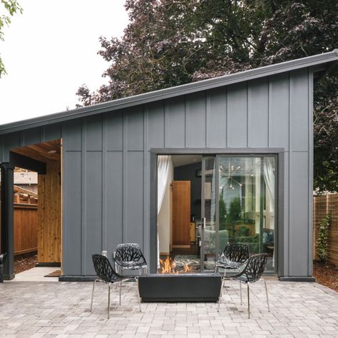 A modern ADU, or Accessory Dwelling Unit (Or guest house, MIL suite, granny flat, etc.) in Portland, Oregon. A shed roof and grey paint with cedar paneling inset at the entry, and a sliding glass door leading out to a pavered patio with a fire pit. Garden Suite Houses, Shed Glass Doors, Adu With French Doors, Adu Guest House, Adu Front Door, Auxiliary Dwelling Unit, Modular Guest House, One Roof House Design, Shed Roof Tiny House