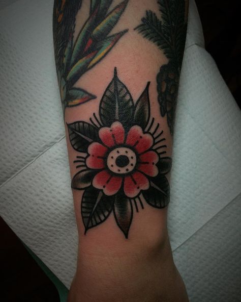 Traditional simple flower tattoo consisting of red and black colors inked on the left wrist Traditional Tattoo Wrist, Traditional Flower Tattoo, Red Flower Tattoos, Simple Flower Tattoo, Mandala Tattoo Sleeve, Traditional Tattoo Flowers, Neotraditional Tattoo, Flower Wrist Tattoos, Traditional Flower