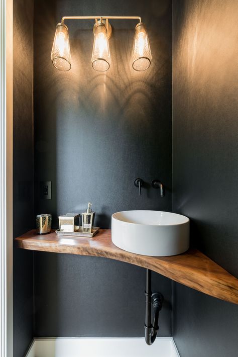 Sherwin Williams Iron Ore paint in this dramatic powder room. A live edge vanity and round vessel sink, matte black fixtures, & gold lighting fixtures complete this statement room.