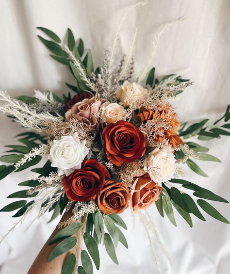 This beautiful artificial wedding bouquet is made from faux flowers of rust orange, cream and ivory, faux pampas grass and silk leaves. They will make the perfect addition to your big day!  This bridal bouquet consists of dahlias, roses with silk eucalyptus and fillers. The stems are wrapped in twine. The bridal bouquet pictured is 12" (30 cm). Bouquet Size Available: Bridal Bouquet- 12" (30 cm) Bridesmaids Bouquets 8" (20 cm) Toss bouquet 7" (17 cm) Matching bridesmaids bouquets, toss bouquet, corsages and boutonnières and other accessories are available. Beach Elopement Bouquet, White And Burnt Orange Wedding Flowers, Eucalyptus And Rust Wedding, Simple Bridesmaid Bouquets Fall, Wedding Bouquets Terracotta, Fall Wedding Bouquets September, Rusty Orange Wedding, Orange Bouquet Wedding, Orange Rose Bridal Bouquet