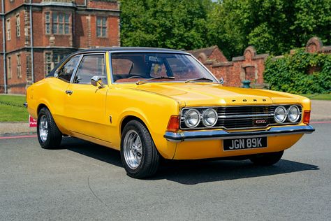 A photograph of a 1971 Ford Cortina MK3. Photographed facing forwards and at an angle the bright yellow, two door car is in the grounds of a stately home with part of the house and walls in the background. Ford Cortina, English Uk, Car Classic, Ford Classic Cars, Coke Bottle, Car Ford, The 1970s, Bottle Design, My Favourite