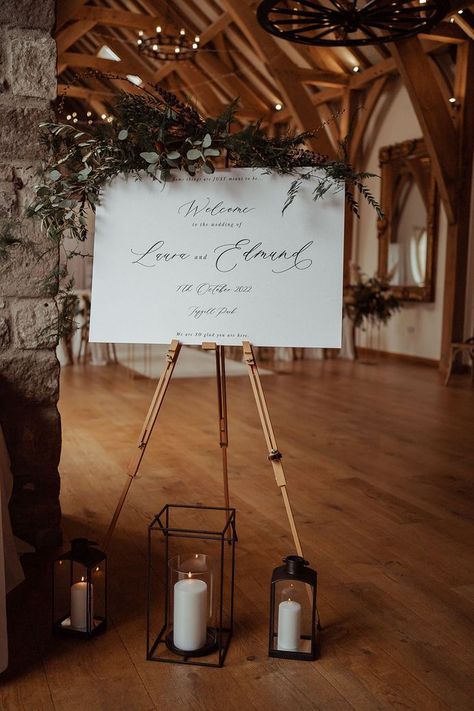 Black and white wedding welcome sign with foliage decor with black lanterns for candles Black Lanterns Wedding, Black Lantern Wedding, Saddle Room, Rustic Wedding Signage, Dog Wedding Outfits, Foliage Decor, Halfpenny London, White Pillar Candles, Rustic Luxe