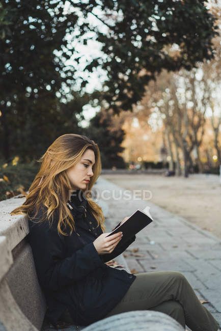 Side view of pretty woman sitting on park bench and reading book. — green, person - Stock Photo | #184794802 Sitting Down Poses Side View, Sitting Reading Book Pose Reference Drawing, Holding Book Side View, Model Reading Book, Side Sitting Pose, Person Reading Reference, Woman Sitting Side View, Sitting On Bench Pose, Sitting Side View Reference