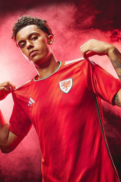 A massive moment for Wales, culminating in a brilliant home top made by adidas. It’s bold red, its got white accents and classic adidas three stripes on the shoulders. With a touch of texture, it’s got just enough to mix things up. And mix things up they will on the world stage this winter. They’ll remember this kit forever, no matter what happens in Group B. Soccer Team Photos, Soccer Team Shirts, Wales Football, Soccer Shop, Adidas Three Stripes, Mens Soccer, Sport Photography, Team Photos, Team Jersey