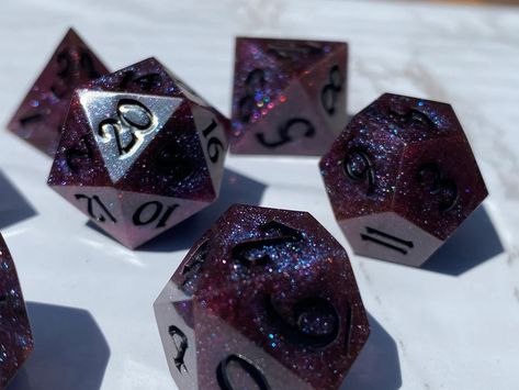 Handmade sharp edge resin dice for Dungeons & Dragons and many other TTRPGs, in a deep black with a purple and blue shine, a dark arcane secret locked away.Custom set style originally conceptualized by: Rachel A. D&d Accessories, Dice Ideas, Cool Dnd Dice, Dnd Tiefling, Dice Goblin, Dice Collection, Dnd Crafts, Purple Stars, Resin Dice