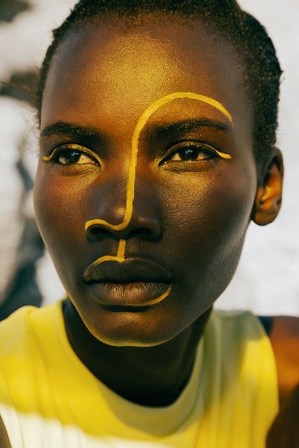 Face Paint Portrait Photography, Lines On Face Makeup, Afro Futuristic Makeup, Bronze Cat Eye Makeup, Afrofuturism Makeup, Yellow Editorial Makeup, Paint On Face Photography, African Inspired Makeup, Editorial Makeup Black Model