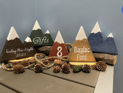 Decorative wooden mountains are perfect for wedding centerpieces, bridal shower decorations, nurseries or rustic decor.   Mountain peaks can be easily customized by adding lettering or numbering.  Mountains can be purchased as single, twin, triple or quad  peaked and can feature white snow caps if desired.  Standard mountain dimensions are approximately 6" x 6" . High quality permanent vinyl personalization (custom) available! We do special requests! Wood Mountain Centerpiece, Wedding Table Numbers Mountains, Mountain Centerpieces, Table Number Photos, Mountain Table Numbers, Wooden Mountains, Family Reunion Keepsakes, Summer Mountain Wedding, Hiking Wedding