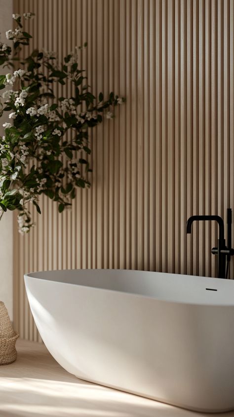 Modern white matte bathtub with black faucet, set against light wooden slats and natural lighting, enhanced by a small plant. Wood Panelling Bathroom Wall, Wood Wall In Bathroom, Panelling Bathroom, Half Bathroom Decor Ideas, Half Bathroom Decor, Vertical Slats, Earthy Living Room, Wood Panelling, Modern Bathtub