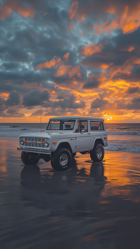 A classic white Ford Bronco stands on the wet sand, illuminated by the captivating hues of a beach sunset, with a sky painted in vibrant orange and deep blue. Ford Broncos, 80s Car, Bronco Vintage, Beach Bronco, Bronco Aesthetic, Vintage Ford Bronco, Vintage Bronco, Bronco Truck Aesthetic, Ford Bronco Aesthetic