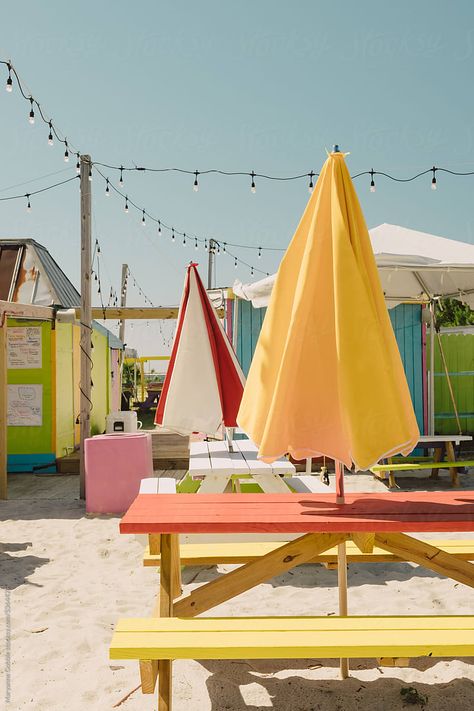 Colorful summer tourist location with empty picnic tables and beach umbrellas. Outdoors patio seating. Outdoor Picnic Table With Umbrella, Picnic Table Umbrella, Picnic Umbrella, Beach Seating, Nautical Patio, Vintage Beach Party, Daycare Playroom, Colorful Picnic, Picnic Table With Umbrella