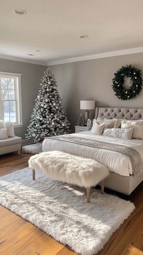 Cozy Christmas bedroom featuring a plush grey bed, fur rug, a large tree, and festive decor against light gray walls. Christmas Bedroom White, Winter Bedroom Colors, Winter Wonderland Room Ideas, Grey Christmas Bedroom, Bedrooms Decorated For Christmas, Aesthetic Christmas Bedroom, Cozy Christmas Bedroom Aesthetic, White Christmas Bedroom, Christmas Bedroom Aesthetic