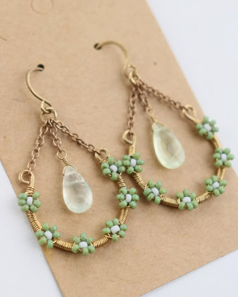 Prehnite Seed Bead Earrings 🌿🍃🟢 It seems that this style of earring is quite popular for me recently so I’ve been making them in various styles and colors! Here is a green seed bead pair, made with prehnite crystals dangling in the center. I listed another flower seed bead pair on my website, along with many new ring options! Feel free to use the link in my bio to check out my recent work :) • • • • • • #seedbeadearrings #seedbead #wireearrings #seedbeadjewelry #wirejewelry #prehnitejewelry... Wire And Bead Jewelry, Hammered Wire Jewelry, Flower Seed Bead, Wire Wrap Rings, Rip Tide, Book Crochet, Wire Wrap Cabochon, Diy Jewelry Rings, Handmade Hoop Earrings