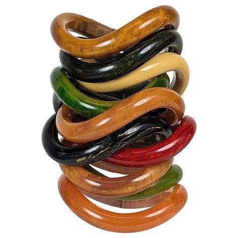 Collection of End of Day Bakelite Squiggle Bracelets from the 1960's likely made of bakelite from an earlier period. Each is shaped like a potato chip and stack perfectly on top of each other. Wonderful colorations which work beautifully in a variety of different configurations. Complete wardrobe includes black, marbleized greens, deep peach, red and banana tones. 11 pieces total. 1960's USA. .5" width. Openings oval in form, 2 3/8" x 2". 1970s Accessories Jewelry, Red Objects, Nigerian Jewelry, Afrocentric Jewelry, Coconut Bowls, Dope Jewelry Accessories, 1960s Jewelry, Bakelite Jewelry, Potato Chip