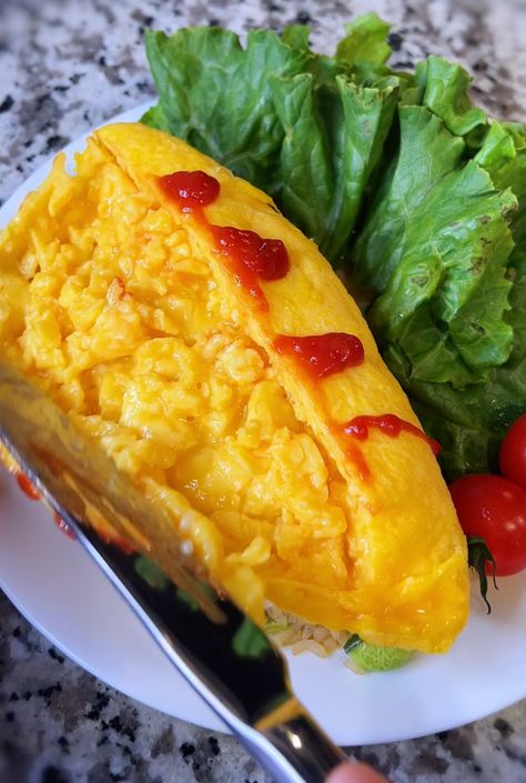 Omurice or omelet rice is fried rice wrapped in fluffy scrambled eggs. To serve, slice the omelet lengthwise, gently open it up like opening up a book, and allow the fluffy scrambled egg inside to bloom. It’s common for Japanese moms to season the fried rice with some ketchup to make it sweet and sour, so that the kids will like them better. Fluffy Egg Omelet, Healthy Football Snacks, Omurice Recipe, Omelet Rice, Japanese Omelet, Japanese Egg, Telur Dadar, Keju Cheddar, Taco Rice