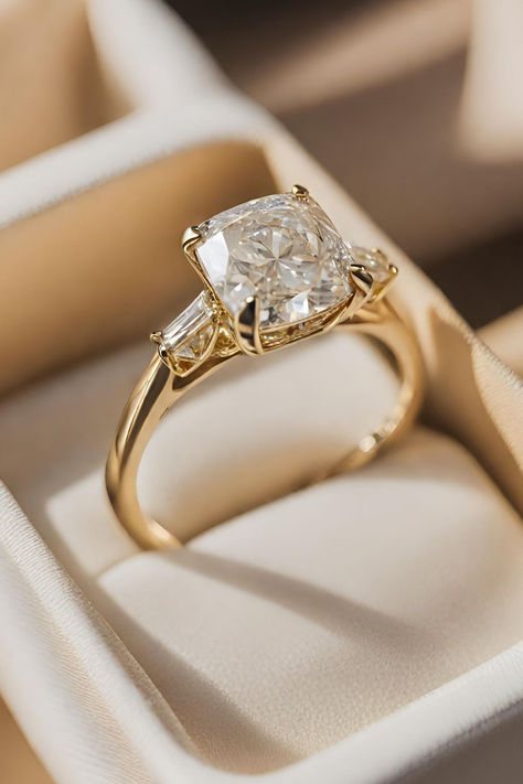 Ranked 10th among our collection of 15 Cushion Cut Diamond Engagement Rings, the Vintage Cushion Cut Diamond Ring with Baguette Side Stones in Yellow Gold showcases a harmonious blend of classic charm and modern sophistication. Click below to discover more captivating designs. Engagement Rings Design Gold, Cushion Engagement Ring Vintage, Gold Engagement Ring With Side Stones, Bevel Setting Engagement Ring, 2 Carat Vintage Engagement Rings, Cushion Cut Engagement Ring With Thick Band, Vintage Diamond Rings Engagement, Elongated Cushion Cut Engagement Ring Platinum, Trilogy Engagement Ring Cushion Cut