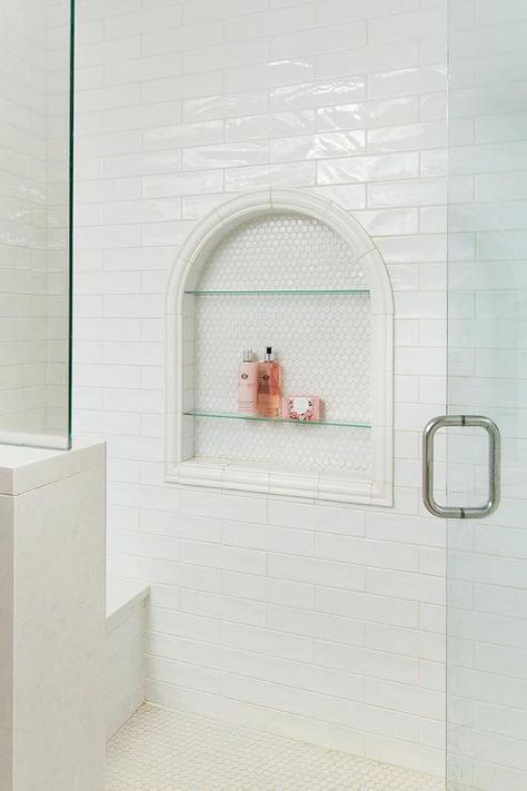 Arched shower niche displaying glass shelves and white hex tiles around a horizontal white glaze tiled wall. Pink Shower Niche, Glass Shower Shelf, Big Shower Niche, Shower Niche Glass Shelves, Arch Shower Niche, Arched Shower Niche, Built In Shower Shelves, Tile Shower Niche, Hex Tiles