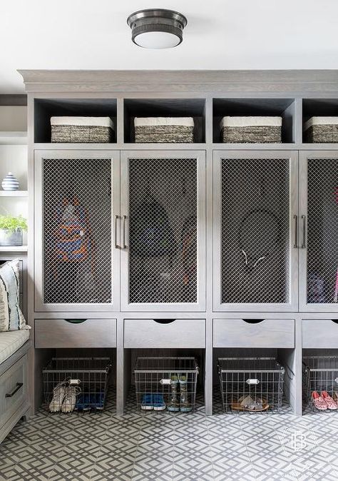 White and gray geometric floor tiles sit beneath vintage metal bins positioned under gray wash wooden drawers and gray wash closed lockers finished with metal lattice door fronts. Garage Lockers, Mudroom Cubbies, Metal Bins, Locker Ideas, Metal Lattice, Mud Room Entry, Mudroom Lockers, Mudroom Laundry Room, Geometric Floor