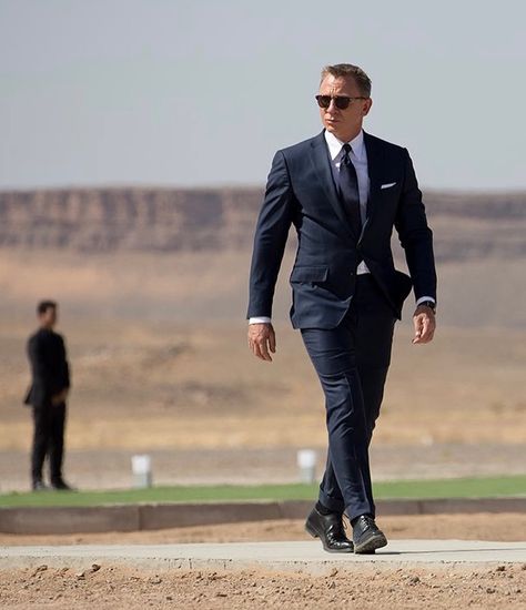 Spectre - Navy Sharkskin “O’Connor” suit. The jacket features straight, padded shoulders with roped sleeve heads. The front has three buttons with narrow notch lapels rolled to the middle button. The jacket is detailed with a single vent, slanted flapped hip pockets, a curved “barchetta” breast pocket and four button cuffs. The trousers are detailed with a wide extended waistband, slide buckle side-adjusters and narrow straight legs and turn-ups from @tomford - White cotton poplin shirt with... James Bond Quotes, Gentlemen Style, Sharkskin Suit, Bond Quotes, Hollywood Movies, Daniel Craig, Cotton Poplin Shirt, Well Dressed Men, Gentleman Style