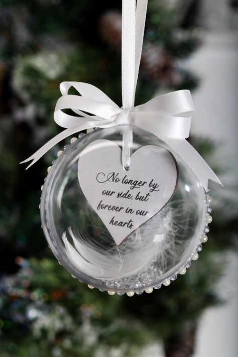 Christmas is a wonderful time of year, but it is also a time for us to remember our loved ones who are no longer with us. Our handcrafted memorial baubles / ornaments are just a little way to keep the memory of our loved ones in our hearts and our home at Christmas time. They contain a wooden heart, a single white feather, a sprinkle of diamanté's and gems around the bauble. This bauble is double sided with the front message 'No longer by our side, but forever in our hearts', reverse message i.e Clear Baubles Ideas, In Memory Christmas Ornaments, Memory Bauble, Angel Ornaments Diy, Vinyl Decoration, Xmas Pictures, Bauble Ornaments, Pink Christmas Decorations, Memorial Ornaments