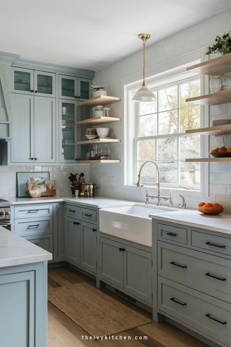 Modern kitchen with light blue cabinets, farmhouse sink, and open shelves by a window. White Oak And Blue Kitchen Cabinets, Cape Cod Style Kitchen, Light Blue Cupboards, Kitchen Cabinets Glass Uppers, White Upper Cabinets Dark Lower, Light Blue Cabinet, Modern Kitchen Cabinet Colors, Blue Kitchen Cabinets Ideas, Blue And White Kitchen Cabinets