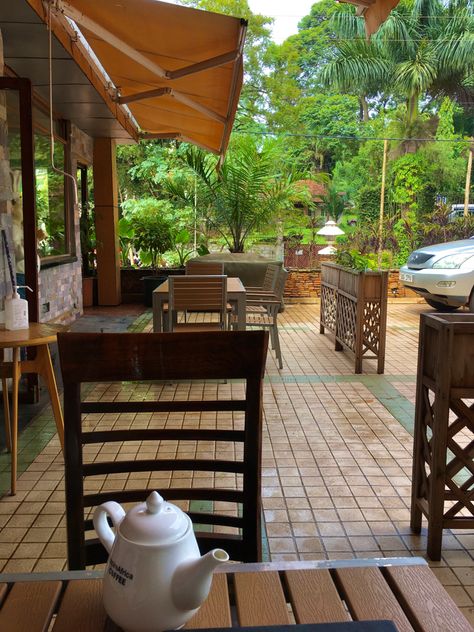 outdoor seating area of a popular cafe in Kampala, Uganda. In the background the beautiful greenery of Uganda is captured, creating a vibrant colour. Pretty Coffee Shop, Ugandan Aesthetic, Living In Africa Aesthetic, Global Village Coffeehouse Aesthetic, African Travel Aesthetic, Bangalore Cafe Aesthetic, Uganda Aesthetic, Uganda Culture Aesthetic, Uganda Kampala