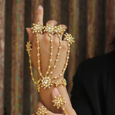 This exquisite set of gold hand harnesses, known as ‘Hathphool’ in traditional jewelry, embodies the essence of intricate craftsmanship and opulence. Each harness features a mesmerizing array of delicate floral motifs, meticulously designed with radiant pearls and glimmering gemstones, cascading gracefully from the rings to the wrists. The gold chains, intricately linked, create a harmonious blend of traditional artistry and contemporary elegance.✨🌸 Prefer a closer look? Book a video call fo... Hand Harness, Bedroom Decor Cozy, Hand Chain, Gold Hands, Traditional Jewelry, Floral Motif, Gold Chains, Lookbook, Chain