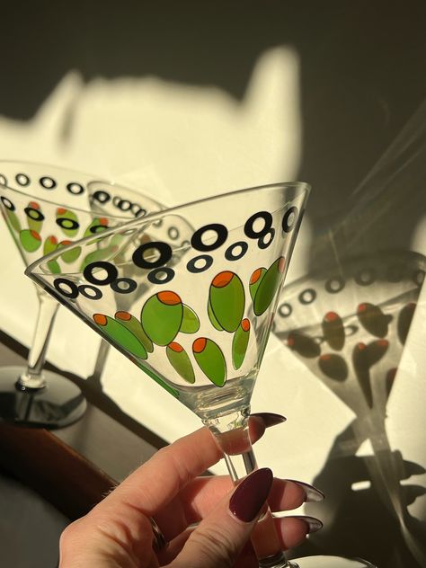 Adorable black accent and green olive pair of plastic martini glasses. Super convincing because they look like glass, these are a perfect party favor because they won’t break if you throw them at anyone. brand: unknown Olive Martini Aesthetic, Fun Martini Glasses, Painted Martini Glasses, Hand Painted Martini Glasses, Colorful Martini Glasses, Martini Olives, Martini Glasses, Christmas Handmade, Green Olive