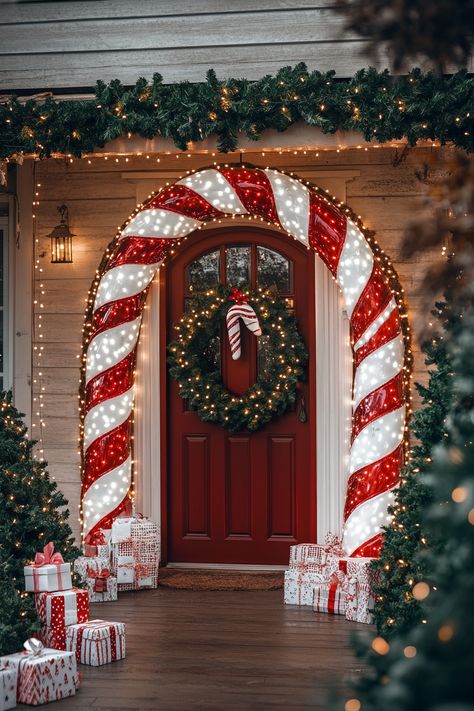 A festive candy cane archway frames a decorated front door with lights, wreaths, garlands, and presents for Christmas. Candy Cane Outdoor Christmas Decorations, Decor With Lanterns, Outdoor Garland, Xmas Projects, Candy Cane Decorations, Outdoor Christmas Decoration Ideas, Outdoor Christmas Decor, Christmas Porch Decor, Christmas Themes Decorations