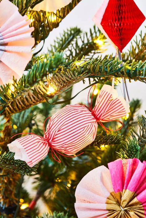 These candy ornaments are as sweet as the real thing. To make these DIY paper ornaments, wrap festive tissue paper around a small ball of cotton stuffing. Twist the paper around the cotton, and secure the ends with string. Use ribbon or wire hooks to place the candies within your tree for a sweet touch to your Christmas decor.#paperornaments #christmasornaments #diyornaments #bhg Paper Diy Ornaments, Diy Candy Christmas Ornaments, Diy Candy Christmas Decorations, Diy Candy Ornaments, Tissue Paper Candy, Rose Diy Paper, Diy Paper Ornaments, Flower With Paper, Peppermint Candy Ornaments