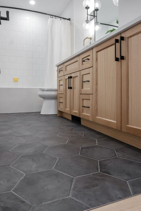 Black White Gray Wood Bathroom, Black Hexagon Tile Bathroom Floor With Wood Vanity, Matte Hexagon Tile Bathroom, Black Floor Restroom, Accent Floor Tile Bathroom, Bathroom Remodel Honeycomb Tile, Dark Hexagon Bathroom Floor, Grey Tile Bathroom Floor Wood Vanity, Guest Bathroom Tile Ideas Floor