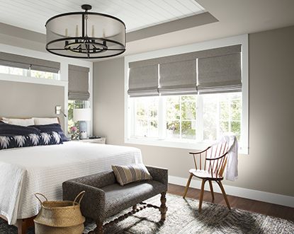 A well-lit, neutral bedroom with large white bed and blue pillows, wooden spindle-back chair, gray bench, and woven basket. Bedroom Paint Color Inspiration, Soothing Bedroom Colors, Relaxing Bedroom Colors, Bedroom Wall Color, Bedroom Paint Color, Calming Bedroom Colors, Calming Paint Colors, Interior Paint Finishes, Ceiling Paint Colors