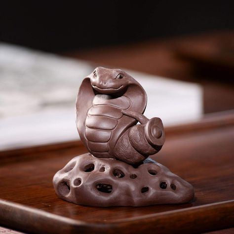 This unique and beautiful tea pet is made of high-quality Yixing purple clay. It is hand-carved in the shape of a king cobra snake, which is a symbol of good luck and prosperity in Chinese culture. The snake is also said to have the power to exorcise evil spirits, making it a popular choice for tea lovers who want to add a touch of luxury and protection to their tea ceremony.

This tea pet is perfect for anyone who appreciates fine craftsmanship and unique objects. King Cobra Snake, Table Ornaments, Cobra Snake, Tea Pet, Yixing Teapot, King Cobra, Pet Pigs, Clay Figurine, Best Tea