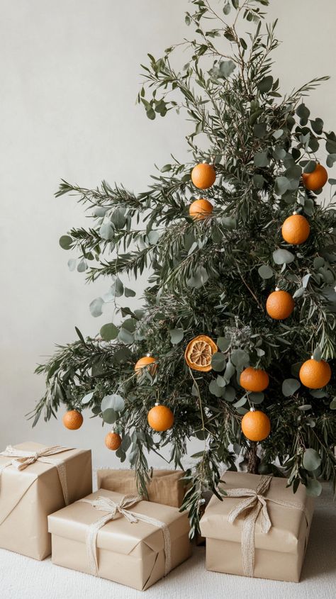 A Christmas tree adorned with eucalyptus and dried orange slices, surrounded by wrapped gifts on a light beige background. Eucalyptus Christmas Decor, Eucalyptus Christmas, Beige Backdrop, Natural Ornaments, Earthy Living Room, Wrapped Gifts, Christmas Planters, Dried Oranges, Dried Orange Slices