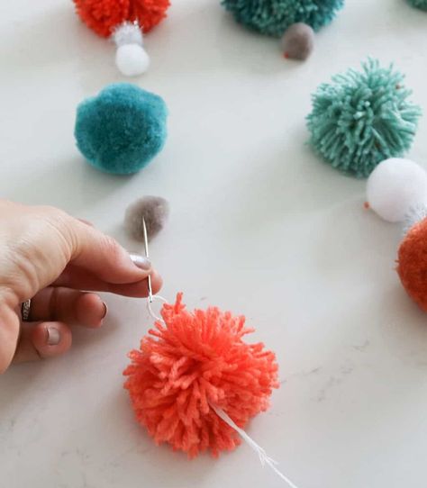 Looking to add a fun pop of handmade color to your home? May I suggest a DIY pom pom wall hanging?    Once you get started it’s easy to knock out a few of these guys, promise.  Gather your supplies:    Dowel rods  Thick string  Needle  Yarn in varying colors   Pom pom tool  (I used a large and small one)  Sharp scissors  Mini store bought pom poms (if you wish)    If you’re not the pom pom making type—good news—you can buy pre-made poms at most craft stores.    While I… Diy Pompoms, Pom Pom Wall Hanging, Pompom Art, Pom Pom Wall, Artsy Decor, Pom Crafts, Sharp Scissors, Elderly Activities, Mini Store