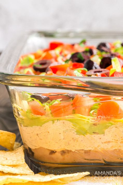 This family favorite taco dip uses refried beans, guacamole, sour cream, cream cheese, taco seasoning and plenty of crunchy toppings. The perfect party dip! Easy Taco Dip With Refried Beans, Nacho Bean Dip, Taco Dip With Cream Cheese Refried Beans, Taco Dip With Refried Beans, Taco Bean Dip, Taco Salad Dip, Cream Cheese Bean Dip, Cream Cheese Taco Dip, Crunchy Toppings