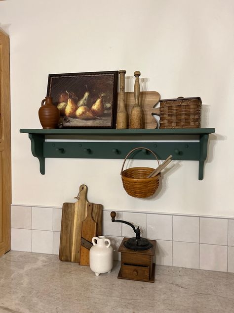 "Add character and functionality to your space with this handcrafted, pine wood peg shelf. Wooden peg shelf with hand crafted corbel ends. Pictured in Basil (color) 36\" (5 peg), this is a versatile shelf that provides both character and functionality to your space. The accent ends on our shelves are hand crafted and not something that can be purchased in a big box store. Each piece is built and painted by hand in our shop. Variations in wood grain make each piece slightly different which adds t Kitchen Window Shelf Decor, Countertop Corner Shelf, Wooden Pegs For Hanging, Hand Painted Shelves, Deep Shelf Decor, Painted Floating Shelves, Shaker Style Home, Vintage Kitchen Shelf, Amazing Gray Paint