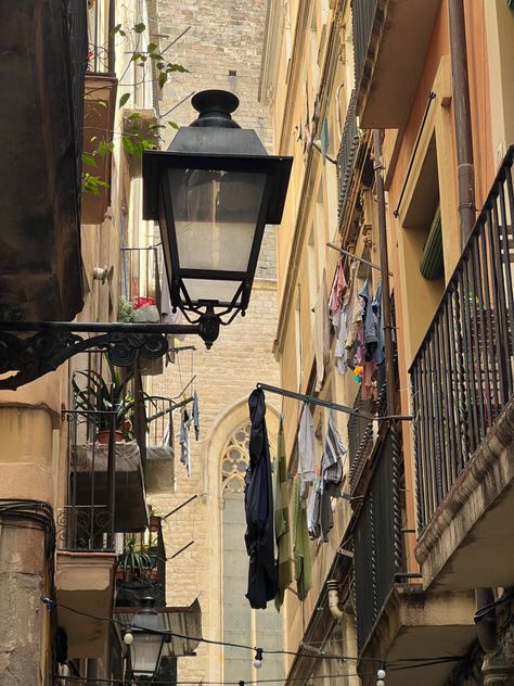 iPhone photo of Barcelona balconies with street lamp, hanging laundry and plants. Gothic church in the background Spain Vintage Aesthetic, Apartment In Spain Aesthetic, Spain Life Aesthetic, Life In Spain Aesthetic, Life In Barcelona, Spain Barcelona Aesthetic, Barcelona Moodboard, Barcelona Living, Barcelona Spain Aesthetic